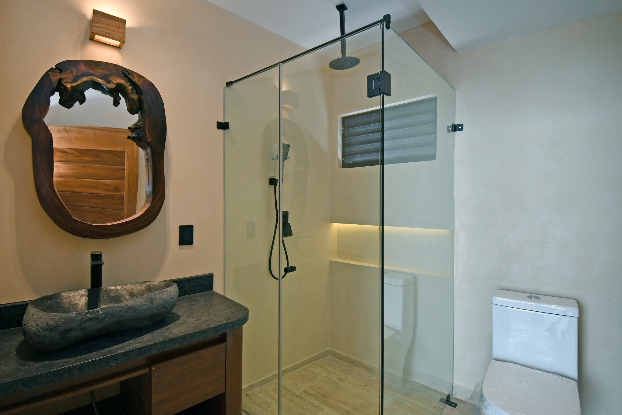 Baño de una villa Zakktal con lavabo artesanal y regadera de vidrio.