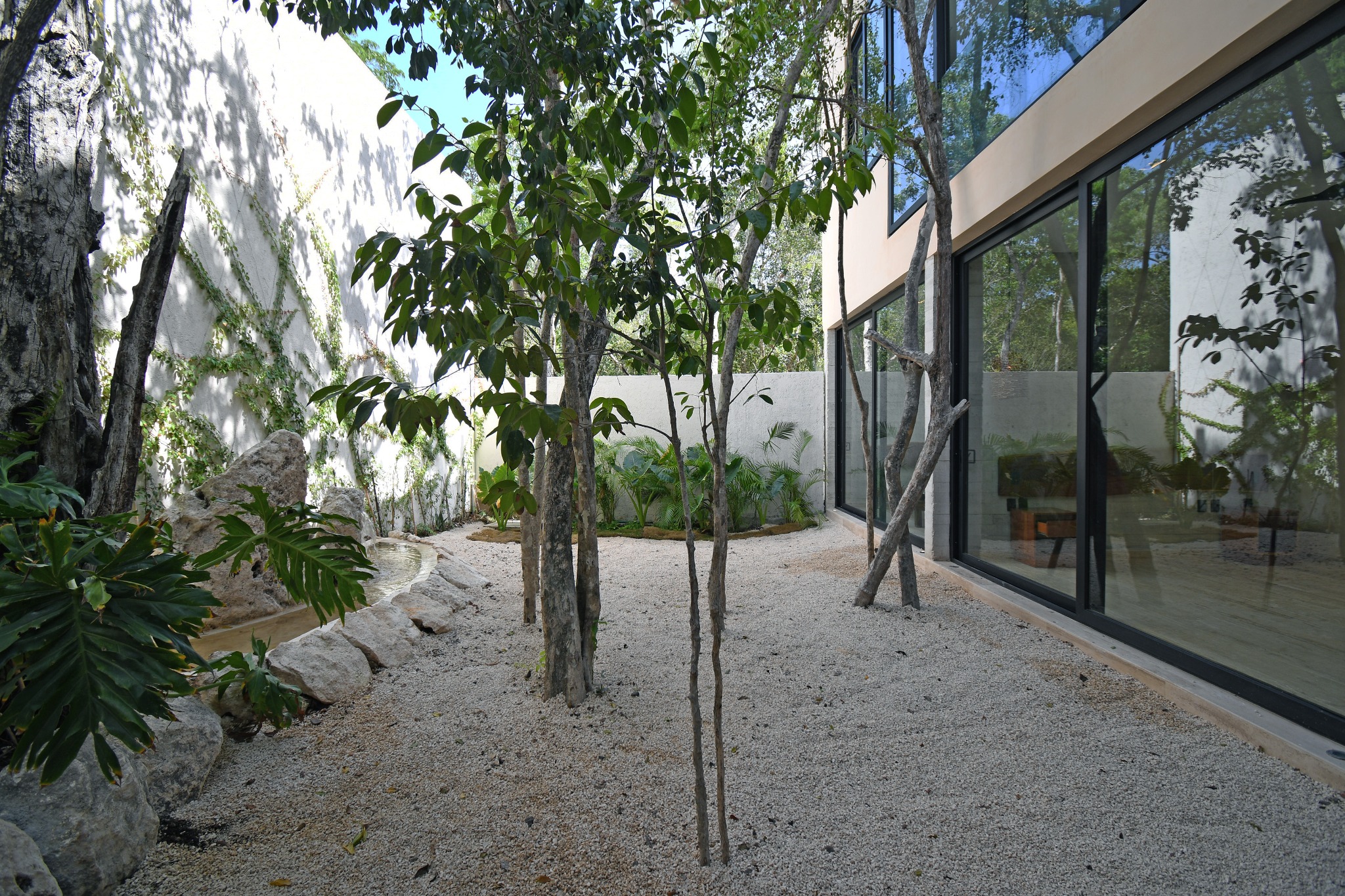 Fachada de vidrio de una villa Zakktal integrada al paisaje tropical.