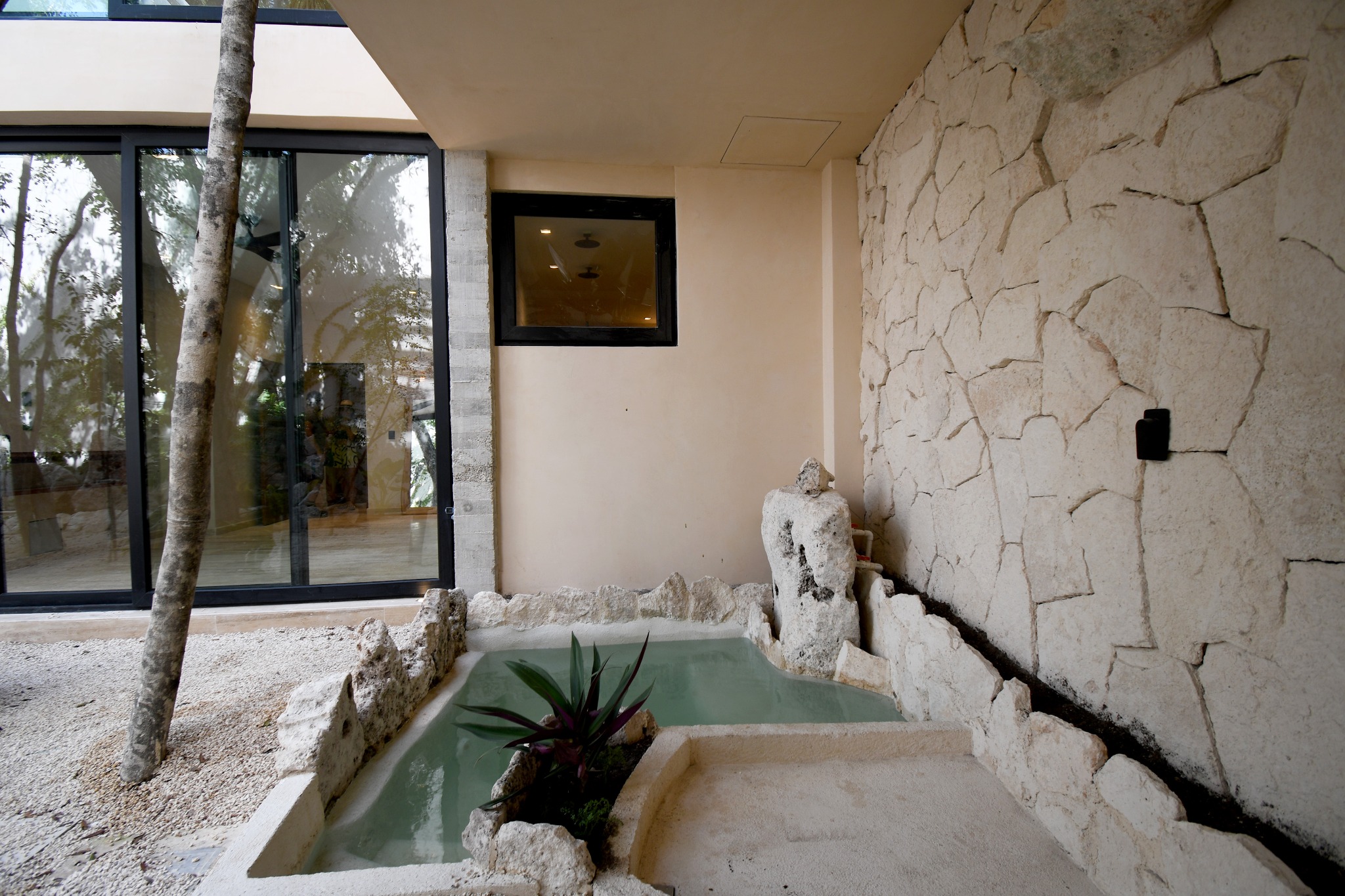 Patio privado de Zakktal con tina, piedra natural y árboles existentes.