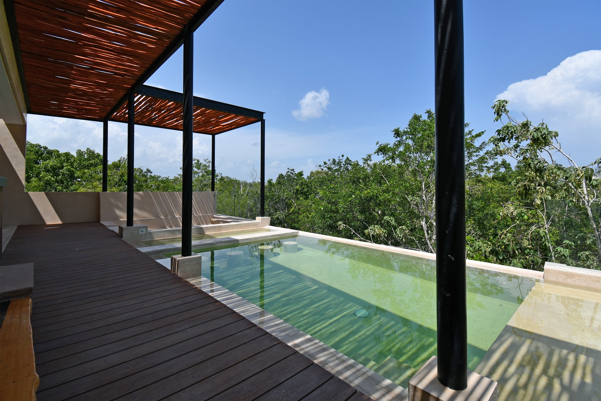 Terraza y piscina de Zakktal con vista a la vegetación de la Riviera Maya.